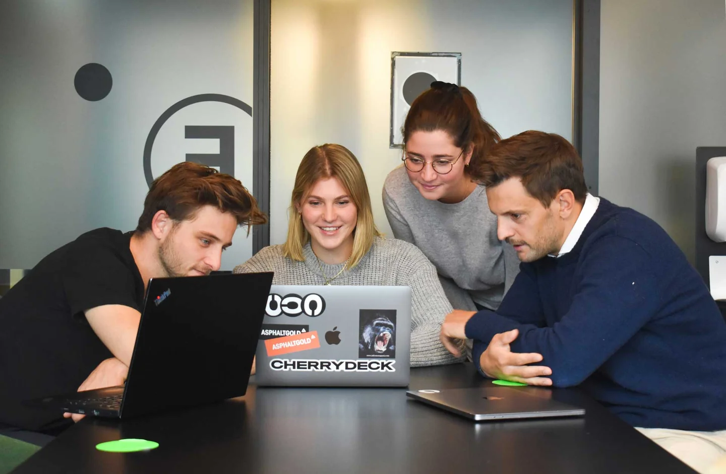 Colleagues gathered around a laptop in a meeting room