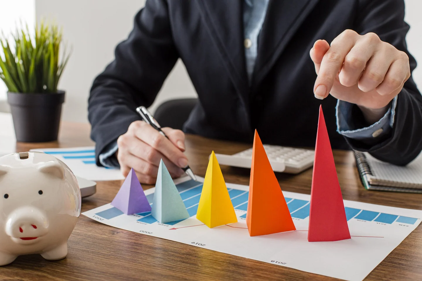 A person arranging colorful paper cones above a printed business chart